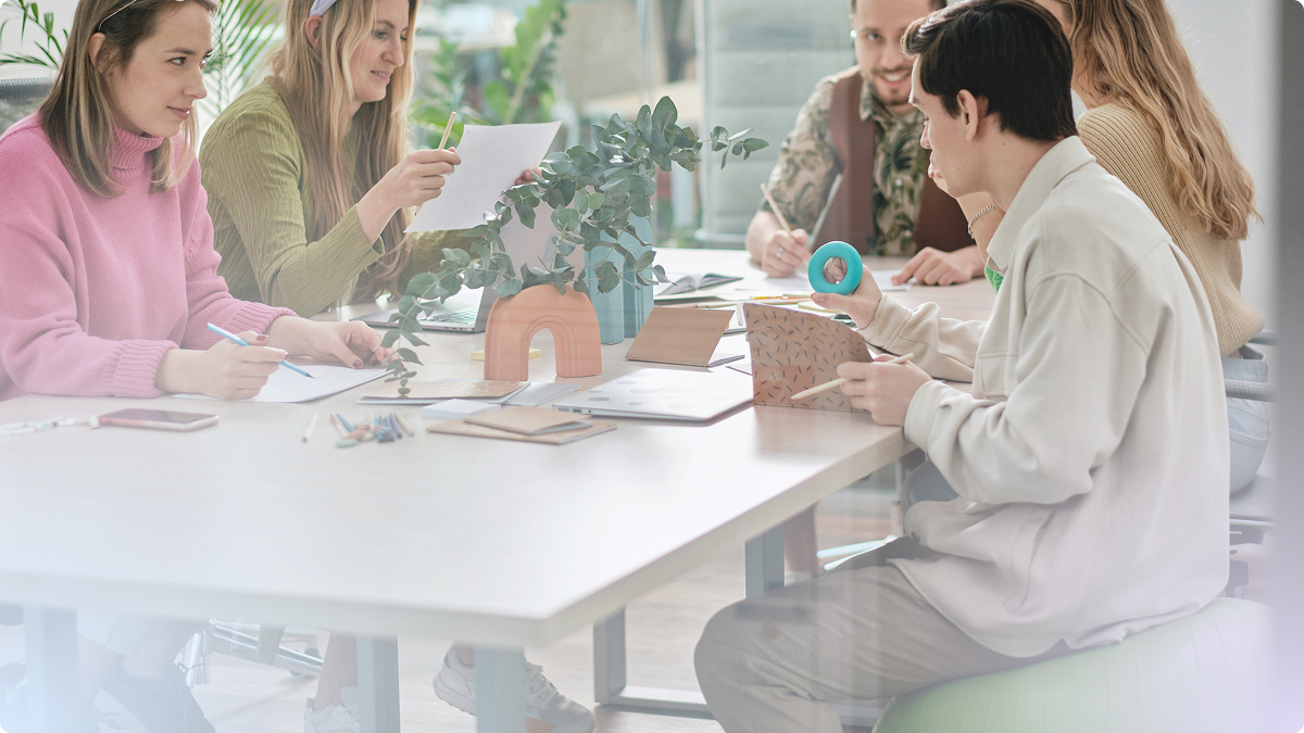 Persone attorno ad un tavolo scrivono e guardano fogli